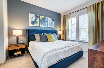 A blue and white bed in a bedroom with windows